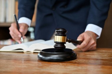 Resmi takım elbiseli profesyonel ve başarılı erkek avukat hukuk kitabı okuyor, ofisinde masasında çalışıyor. kırpılmış resim