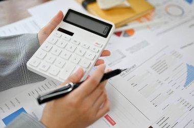 Yakın plan görüntü, iş kadını ya da kadın finans çalışanı hesap makinesi kullanıyor, mali rapor üzerinde çalışıyor..