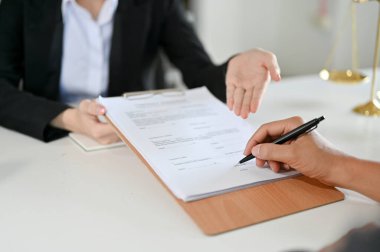 Businessman client sign his signature on the agreement paper in front of the professional female lawyer. cropped, close-up image