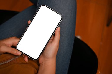 Tepeden çekimde, kadın ofis masasında oturmuş akıllı telefon kullanarak biriyle sohbet ediyor ya da internetten bilgi topluyor. Telefon beyaz ekran modeli