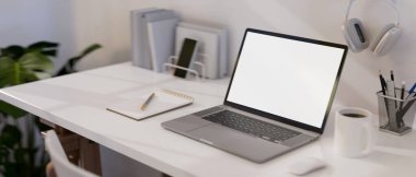 Modern white office desk with portable notebook laptop white screen mockup and office accessories. close-up image. 3d rendering, 3d illustration