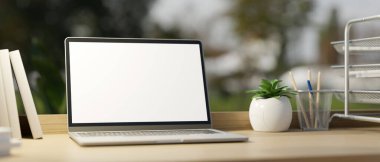 Görüntüyü yaklaştır. Ofis çalışma masasında dizüstü bilgisayar, beyaz ekran maketi ve ofis malzemeleri var. 3d görüntüleme, 3d illüstrasyon