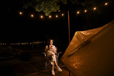 Güzel Asyalı dişi milenyum geceleri kamp alanındaki güzel gökyüzüne bakarken sıcak kakao ya da kahve yudumluyor..