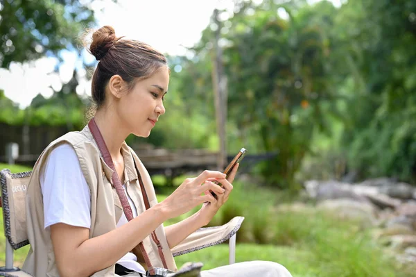 Attractive Young Asian Female Traveler Sitting Camping Chair Using Smartphone — Foto de Stock