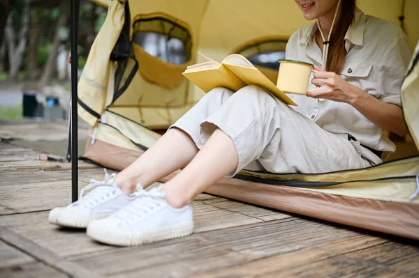 Kesilmiş görüntü, kamp alanındaki çadırda en sevdiği romanı ya da kitabı okurken rahatlarken aromalı sıcak çay içen bir kadın..