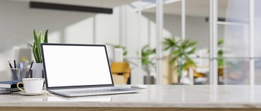 Laptop beyaz ekranlı modern beyaz çalışma masası, bir fincan kahve, aksesuarlar ve bulanık ofis arkaplanı üzerine kopyalama alanı. 3d görüntüleme, 3d illüstrasyon