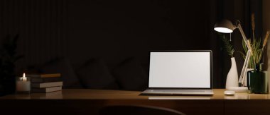 Workspace at night, Laptop computer white screen mockup under the light from table lamp on wooden tabletop over the dark background. 3d rendering, 3d illustration