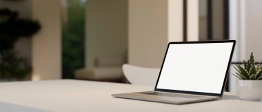 Notebook laptop white screen mockup is on white tabletop over blurred living room background. close-up image. 3d rendering, 3d illustration