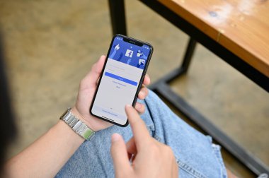 Chiangmai, Thailand - Aug 25 2022: A female using her smartphone to login on her Facebook. mobile phone with Facebook login page on screen. close-up image
