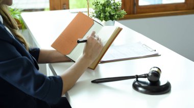 Close-up image, A female lawyer or business legal consultant taking notes on her personal notebook, listing something on the notebook page.
