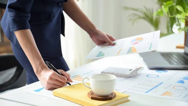 Professional businesswoman or female analyst working on a financial data report at her office desk. cropped image