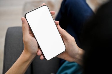 close-up image, A young Asian man using his smartphone, holding a mobile phone white screen mockup.