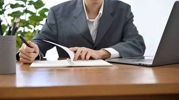 Professional Asian businessman in formal suit working at his office desk, checking and reviewing business paperwork. cropped image