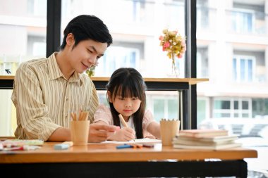 A lovely young Asian girl concentrates on learning art in the art workshop with her teacher. Creative kids' activity and hobby concept