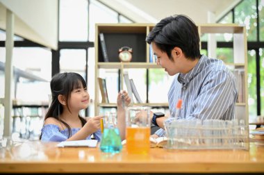 The pretty young Asian girl enjoys learning science, doing some science experiment for kids with her teacher. 