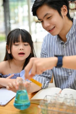 Portrait, Cute young Asian girl is excited and enjoying doing a science experiment with her teacher. Scientific activity and kids' concept
