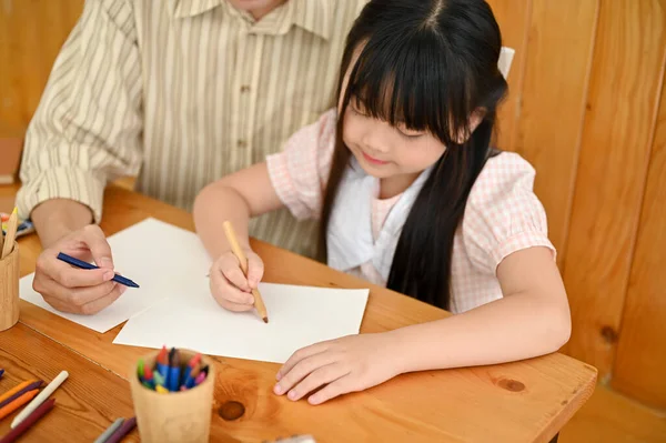 Cute Young Asian Girl Concentrating Doing Homework Paper Her Dad — Stockfoto