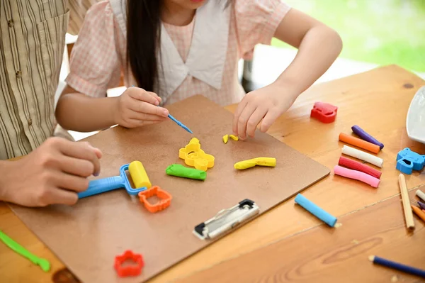 Above view, A cute little young Asian girl sculpting and moulding play dough with her dad at home. Creative art activity for kids concept.