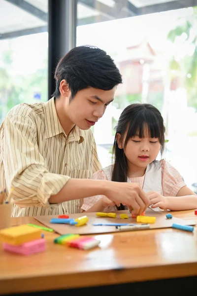 Portrait, Happy and cute Asian dad and daughter playing play dough together on their free time at home. Happy family concept