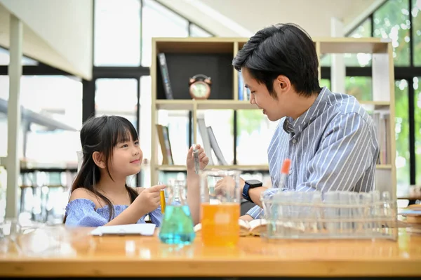 The pretty young Asian girl enjoys learning science, doing some science experiment for kids with her teacher. 
