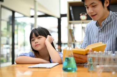 Cute Asian little girl feeling bored and sleepy during studying science with her private teacher.