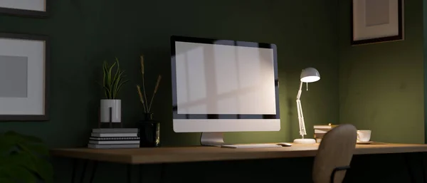 Modern home office workspace at night with pc desktop computer white screen mockup, light from table lamp and accessories on table over the green wall. dark workspace. 3d rendering, 3d illustration
