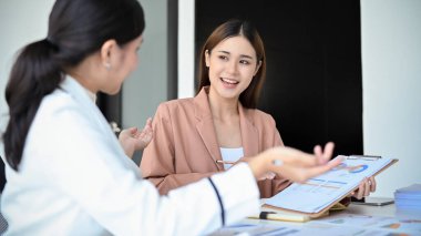 Yetenekli ve zeki bir Asyalı kadın finans analisti ya da muhasebeci toplantıda kadın patronuna finansal yatırım planını sunuyor..