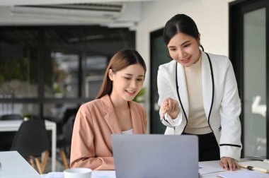 Profesyonel ve nazik Asyalı bayan yönetici ya da bayan patron yeni asistanına bir görev için yardım, eğitmenlik ve eğitim veriyor..