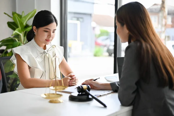 Beautiful Asian female client meets with her personal lawyer or business legal consultant for sign an agreement and counseling for her lawsuit.