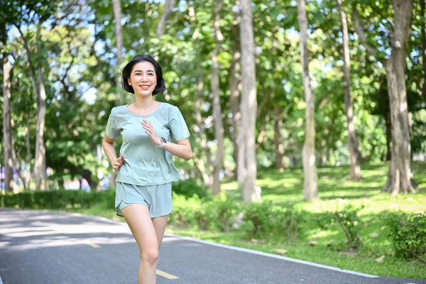Aktif ve formda Asyalı kadın sabahları şehir parkında koşuyor ve koşuyor. Sağlıklı yaşam tarzı kavramı