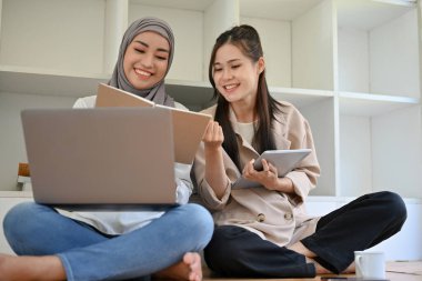 Güzel Asyalı genç kız üniversite öğrencisi kütüphanede Müslüman arkadaşıyla birlikte çalışıyor, bir çalışma projesi yapıyor ve bir kitap hakkındaki bilgileri birlikte araştırıyorlar..