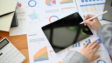 Masasında çalışan profesyonel bir iş kadını ya da finansal verileri analiz etmek için dijital tablet kullanan bir finans analisti..