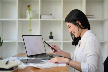 Ofis masasında çalışan güzel Asyalı iş kadını ya da kadın muhasebeci, iş satış raporlarını analiz ediyor..