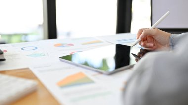 Ofis masasında çalışan profesyonel bir iş kadını veya finans analisti, finansal verileri analiz etmek için dijital tablet kullanıyor. kırpılmış resim