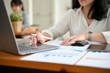 Ofis masasında çalışan başarılı bir iş kadını ya da finans analisti, finansal verileri analiz etmek için dizüstü bilgisayar kullanıyor. kırpılmış resim