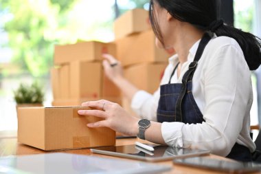 Çekici genç Asyalı kadın e-ticaret girişimi, nakliye paketlerini ofiste hazırlıyor. kırpılmış resim