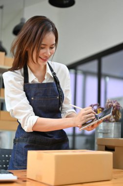 Çekici Asyalı bayan küçük işletme sahibi müşterinin adresini kontrol etmek için tablet dokunmatik ped kullanıyor. Çevrimiçi alışveriş konsepti