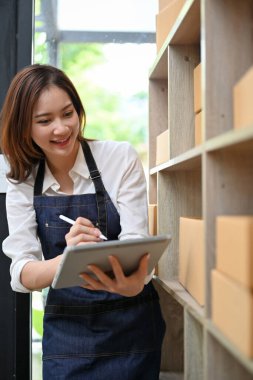 Güzel Asyalı genç bayan internet girişimi sahibi stoktaki ürün stoğunu kontrol ediyor..