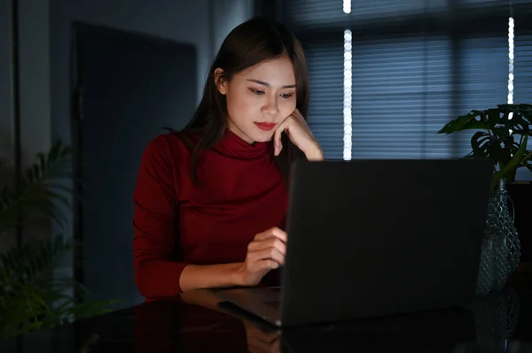 Talented and hard-working young Asian businesswoman or female office employee working in the office at night.