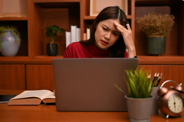 A stressed and serious young Asian businesswoman or female manager is having a laptop computer problem or business problem.