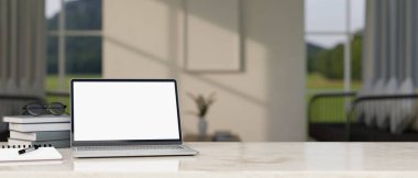 Arka planda bulanık modern oturma odasının üzerine dizüstü bilgisayar, beyaz ekran maketi, kitap ve fotokopi alanı olan modern ev çalışma alanı. 3d görüntüleme, 3d illüstrasyon