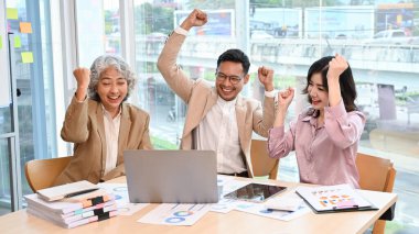Asyalı neşeli ve başarılı iş adamları toplantı odasında başarılarını kutluyorlar. Proje galibiyeti, hedef başarısı, zafer gösterme.