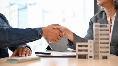 Profesyonel bir üst düzey Asyalı kadın emlakçı ya da emlakçı toplantıdan sonra erkek bir müşteriyle tokalaşıyor. kırpılmış ve yakın plan resim