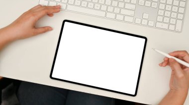 Üst görünüm, dijital tablet dokunmatik tablet beyaz ekran modeli modern beyaz ofis masasında. Masasında dijital tablet kullanan bir kadın..