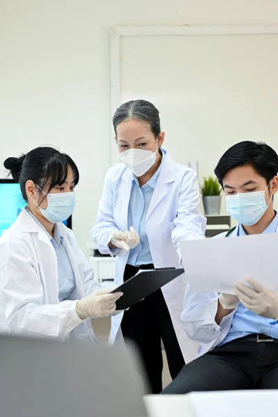 一名专业而成功的亚洲资深女医生专家主管在实验室培训和教授两名年轻的亚洲初级专家 — 图库照片
