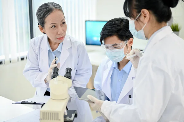 A professional Asian senior female medical specialist supervisor training two young Asian junior medical specialist in the laboratory.