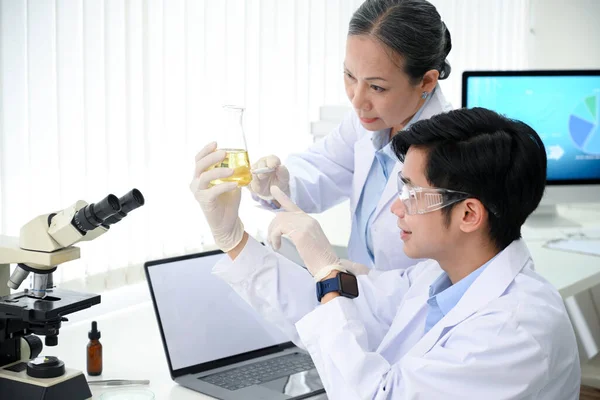 아시아의 책임자가 기술자와 사무실에서 의료용 액체를 연구하고 테스트하고 있습니다 — 스톡 사진