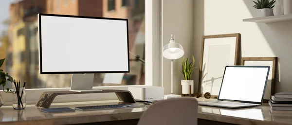 Modern office desk workspace with computer and laptop white screen mockup, table lamp and accessories on table against the window. close-up image. 3d rendering, 3d illustration