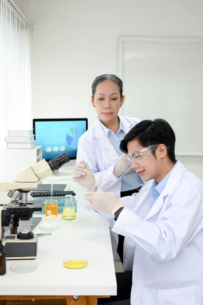 기사보기 아시아의 과학자가 자신의 새로운 과학자에게 자신의 실험용 화학물을 조절하는 — 스톡 사진
