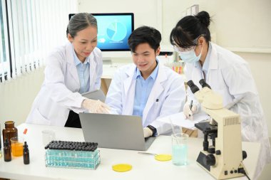 Yetenekli ve profesyonel Asyalı bilim adamları veya kimyagerlerden oluşan bir ekip laboratuvar ofisindeki projelerinde beyin fırtınası yapıyorlar..
